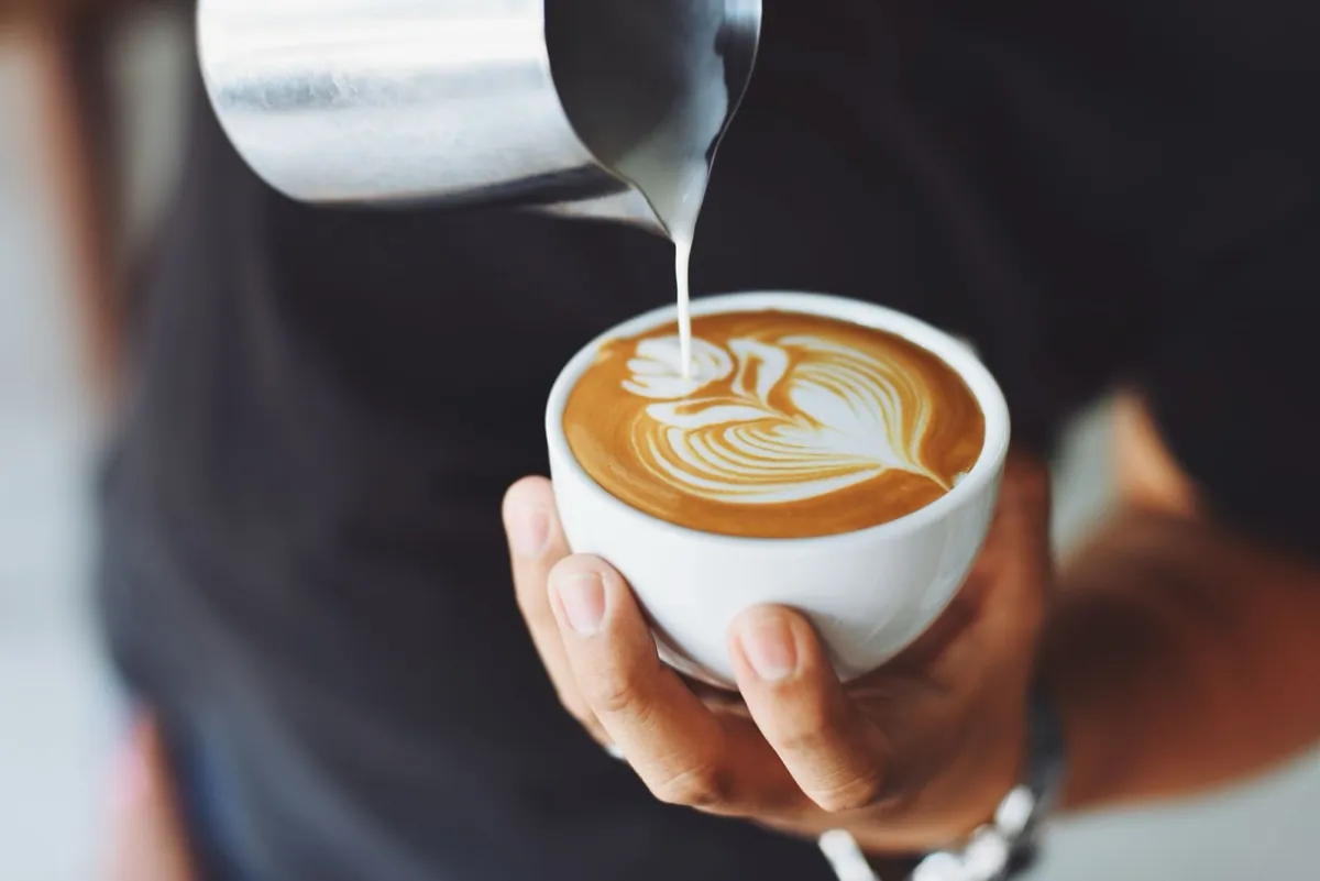 Barista pouring latte art into a cup, a website for a café step by step